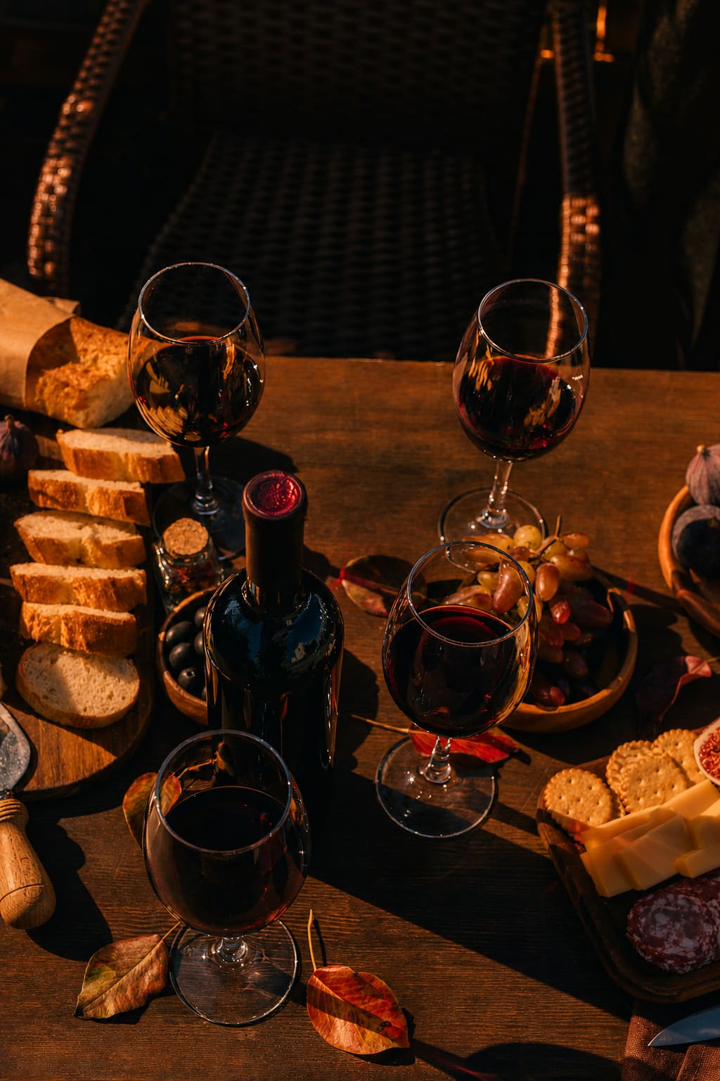Red wine poured at a table with bread, cheese and figs